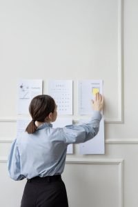 Une femme organise un agenda mural au bureau montrant la stratégie et la planification.