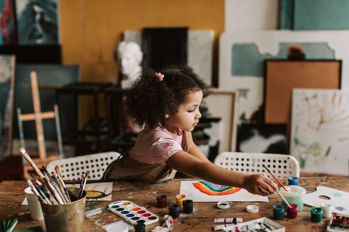Fille en train de peindre à une table avec divers fournitures artistiques