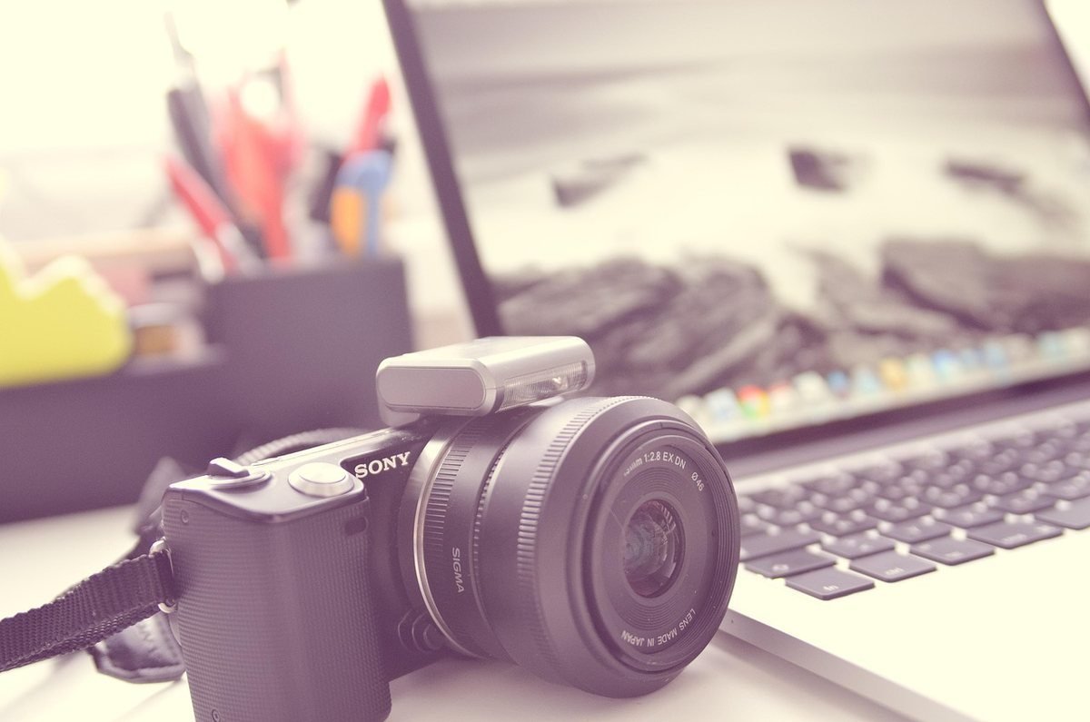 Appareil photo Sony sur un bureau devant un ordinateur portable affichant une image de plage