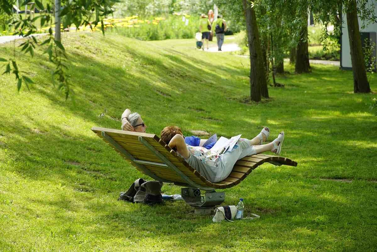 Une personne se détend sur un banc en bois dans un parc verdoyant Une personne se détend sur un banc en bois dans un parc verdoyant