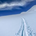 Piste de ski en poudre sur une montagne enneigée sous un ciel bleu avec nuages