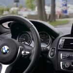 Vue du cockpit d'une BMW, main tenant le volant, navigation affichée