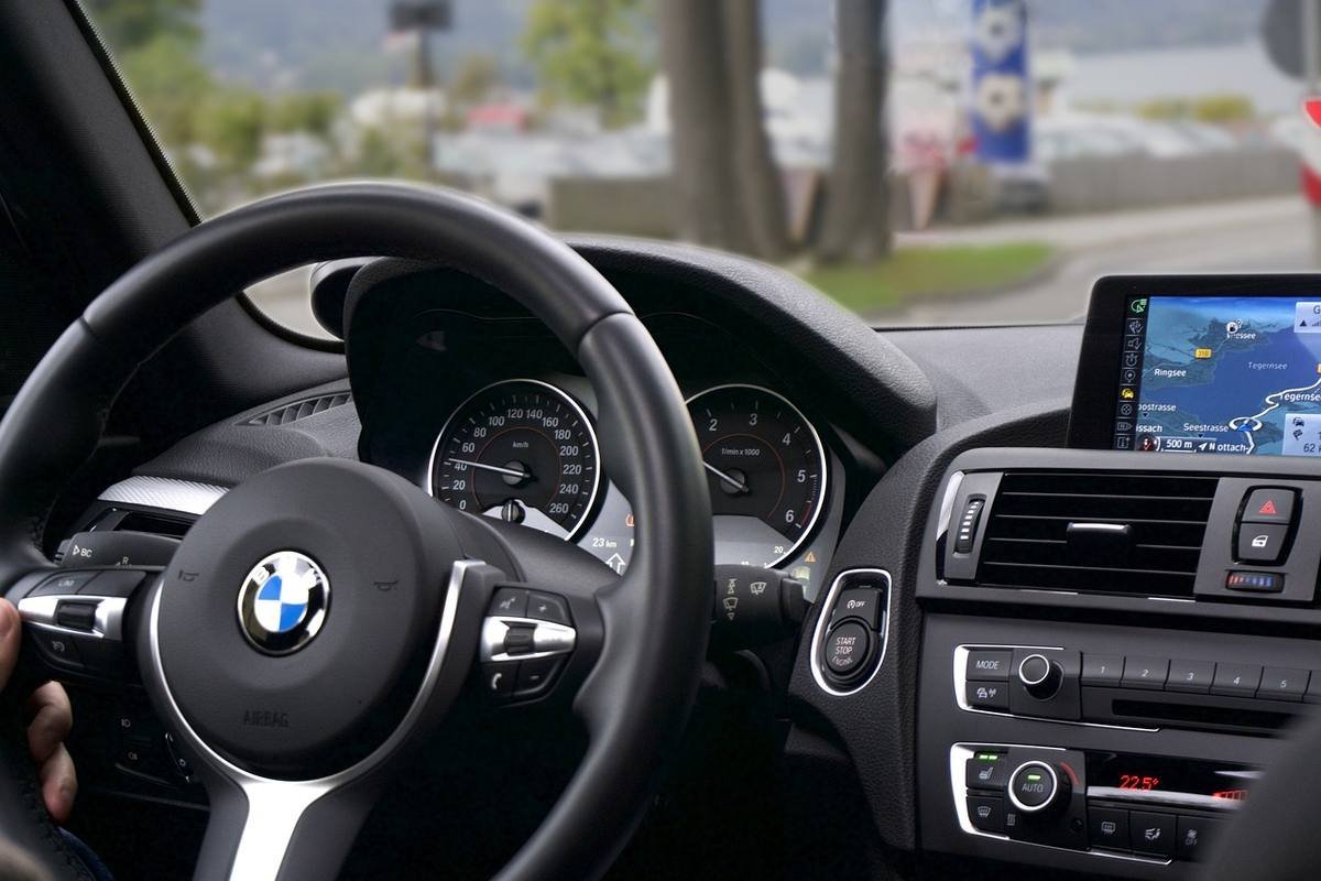 Vue du cockpit d'une BMW, main tenant le volant, navigation affichée